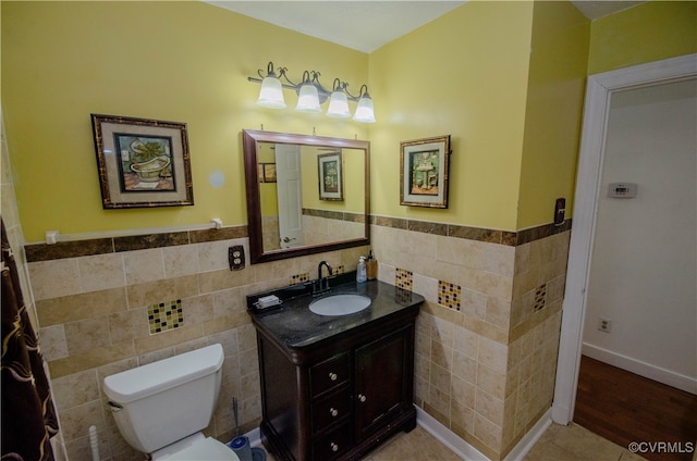 bathroom with wood-type flooring, vanity, toilet, and tile walls