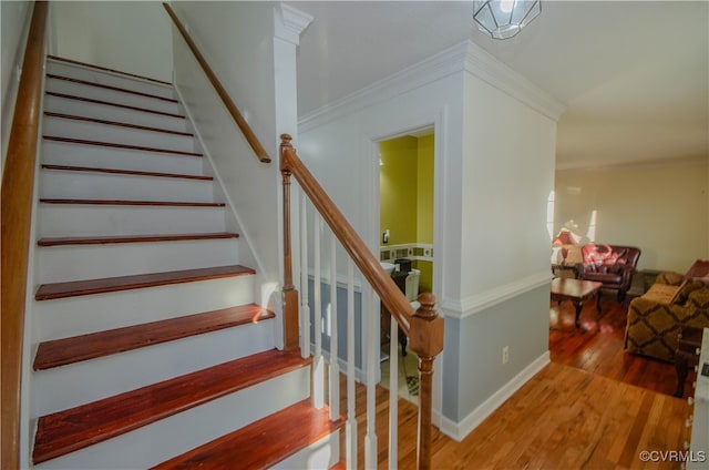 staircase with wood-type flooring and ornamental molding