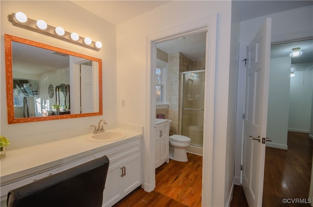 bathroom with hardwood / wood-style floors, vanity, toilet, and walk in shower