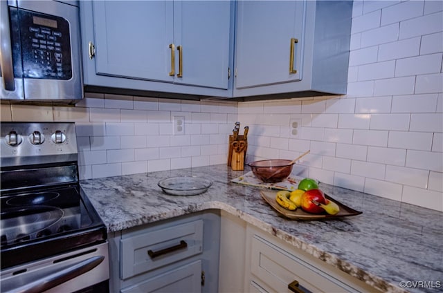 kitchen with tasteful backsplash, light stone countertops, and stainless steel appliances