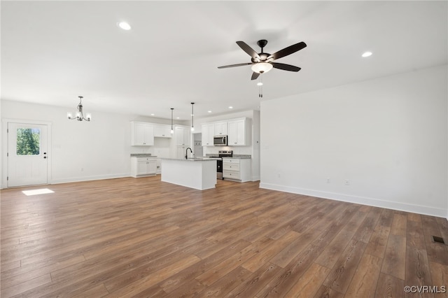 unfurnished living room with hardwood / wood-style floors, ceiling fan with notable chandelier, and sink