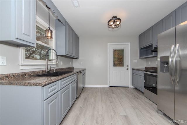 kitchen with appliances with stainless steel finishes, light hardwood / wood-style floors, gray cabinets, and sink