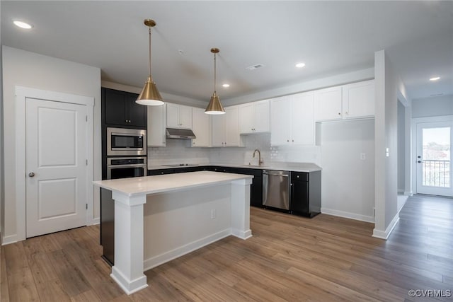 kitchen with pendant lighting, sink, light wood-type flooring, tasteful backsplash, and stainless steel appliances