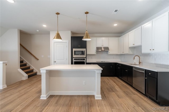 kitchen featuring appliances with stainless steel finishes, light wood-type flooring, pendant lighting, and sink