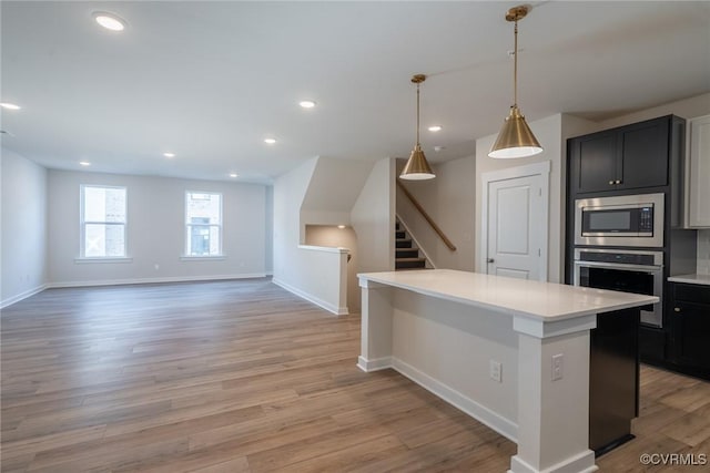 kitchen with hanging light fixtures, light hardwood / wood-style flooring, a kitchen island, and stainless steel appliances