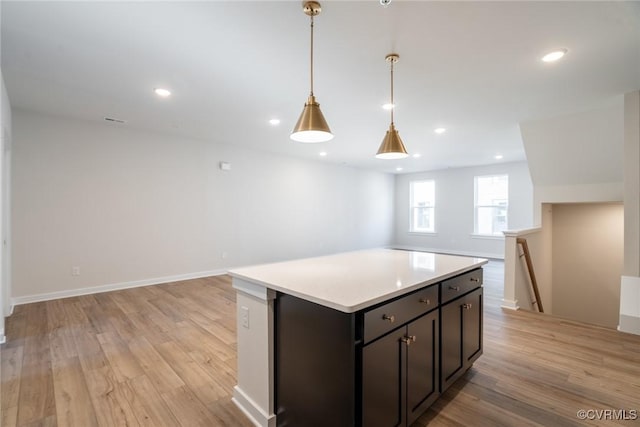 kitchen featuring a kitchen island, dark brown cabinetry, hanging light fixtures, and light hardwood / wood-style flooring