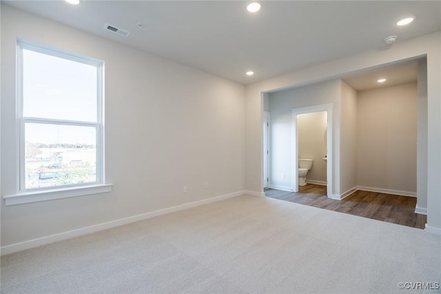 unfurnished bedroom featuring ensuite bathroom and wood-type flooring