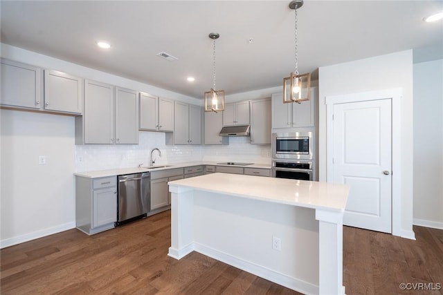 kitchen featuring a center island, backsplash, sink, dark hardwood / wood-style floors, and appliances with stainless steel finishes