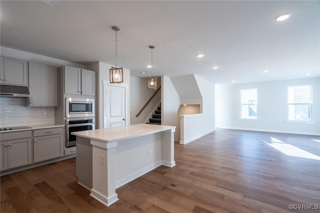 kitchen featuring hardwood / wood-style floors, stainless steel appliances, a kitchen island, and gray cabinetry