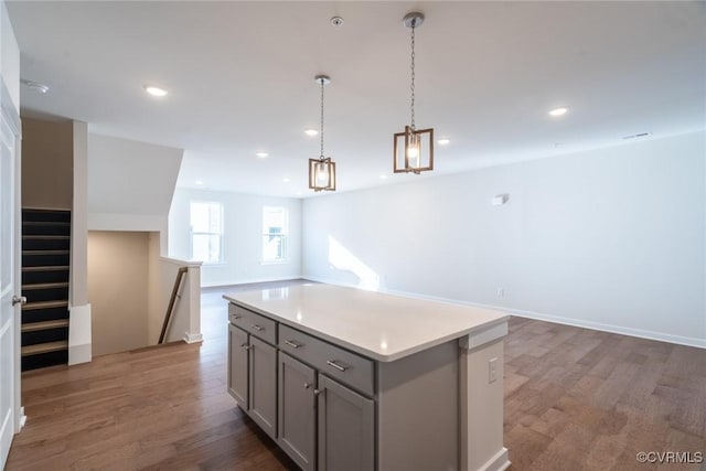 kitchen featuring gray cabinetry, decorative light fixtures, a kitchen island, and dark hardwood / wood-style flooring