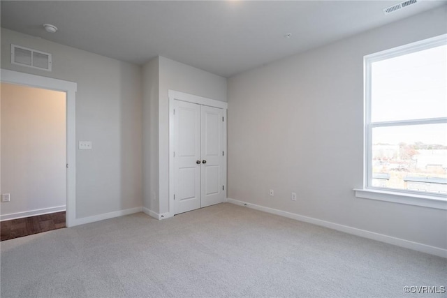 unfurnished bedroom featuring a closet and light colored carpet