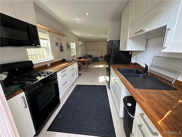 kitchen with wood counters, light hardwood / wood-style floors, white cabinetry, and black appliances