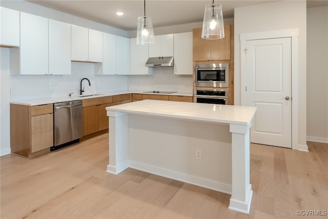 kitchen with white cabinets, sink, light hardwood / wood-style floors, appliances with stainless steel finishes, and a kitchen island