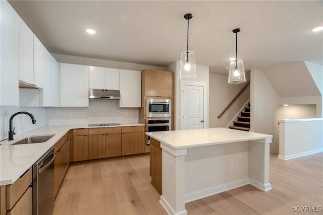 kitchen with white cabinetry, sink, stainless steel appliances, pendant lighting, and light wood-type flooring