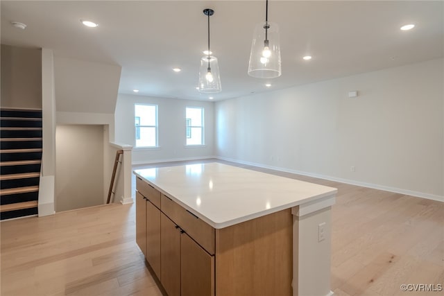 kitchen featuring a kitchen island, hanging light fixtures, and light hardwood / wood-style flooring