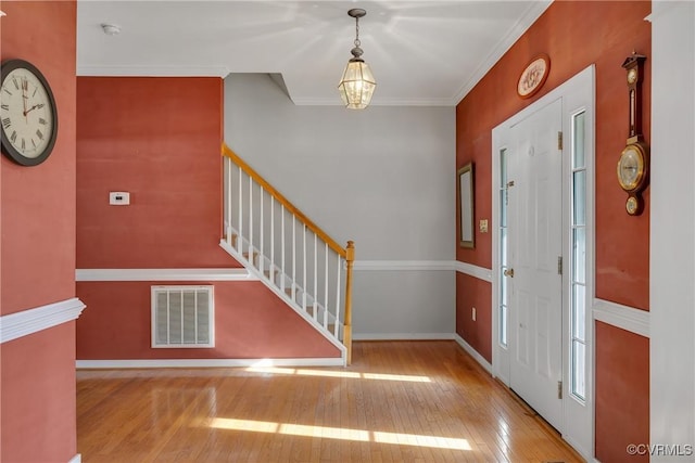 foyer with crown molding and light hardwood / wood-style flooring