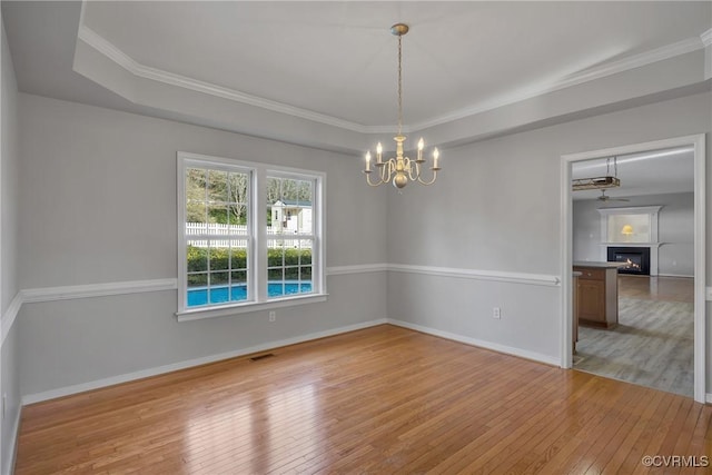 spare room featuring light wood-type flooring, crown molding, and a chandelier