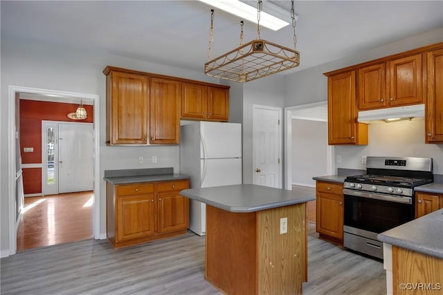 kitchen with gas range, pendant lighting, white refrigerator, a center island, and light hardwood / wood-style floors