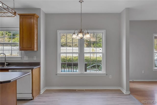 unfurnished dining area featuring a chandelier, sink, and light hardwood / wood-style floors