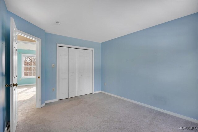 unfurnished bedroom with a closet and light colored carpet