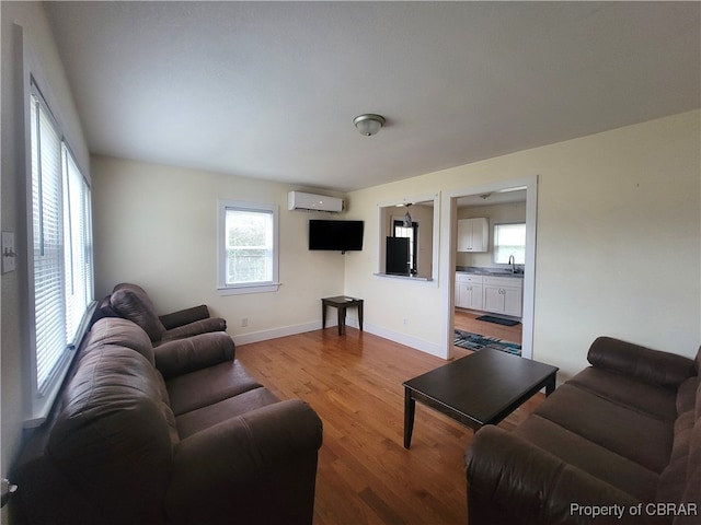 living room featuring a wall mounted AC, sink, and light hardwood / wood-style floors