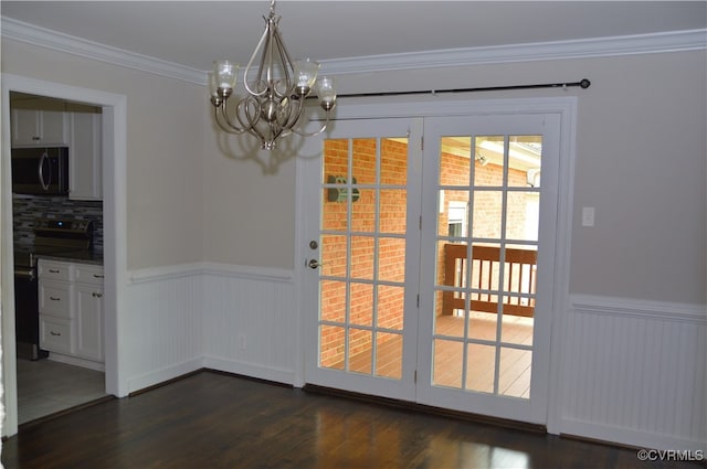 doorway to outside with ornamental molding, dark wood-type flooring, and an inviting chandelier