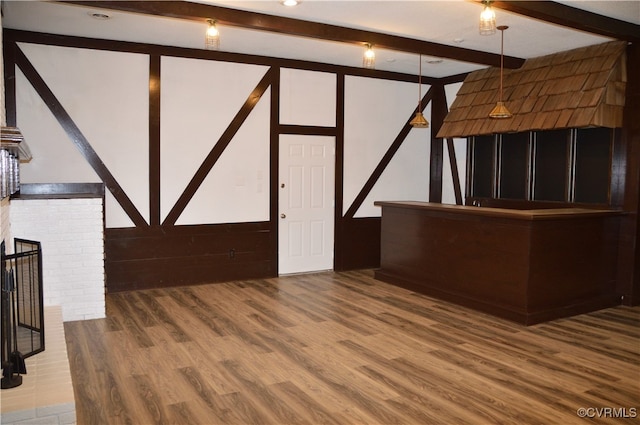 unfurnished living room featuring beam ceiling, wood-type flooring, and a brick fireplace