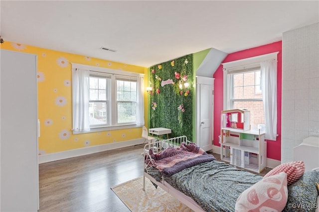 bedroom with hardwood / wood-style floors and multiple windows