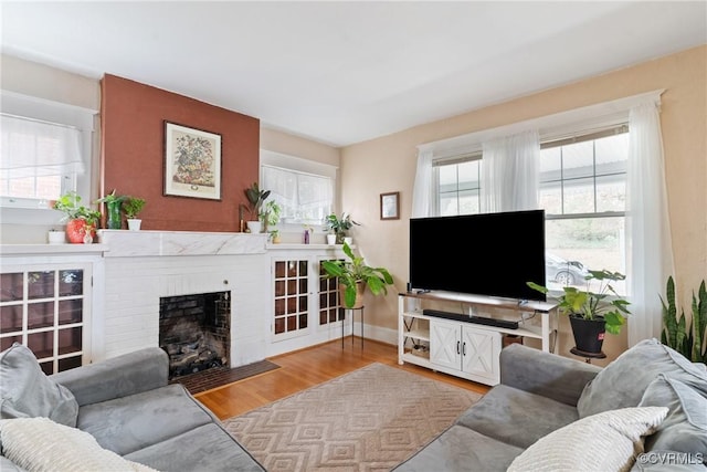 living room with light hardwood / wood-style floors and a brick fireplace