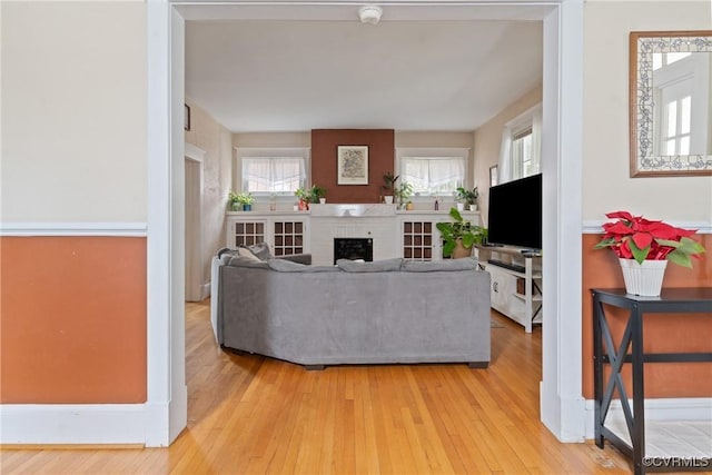 living room with light hardwood / wood-style floors and a brick fireplace