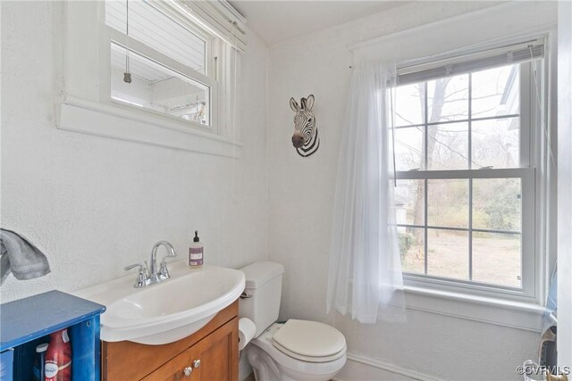 bathroom with a wealth of natural light, vanity, and toilet