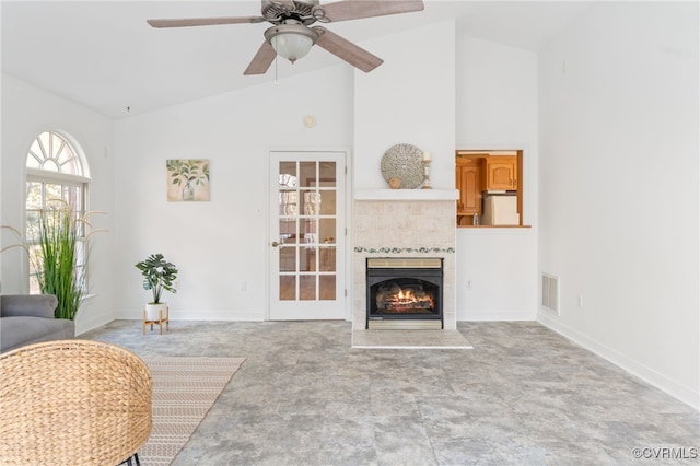 living room featuring high vaulted ceiling, ceiling fan, and a tile fireplace