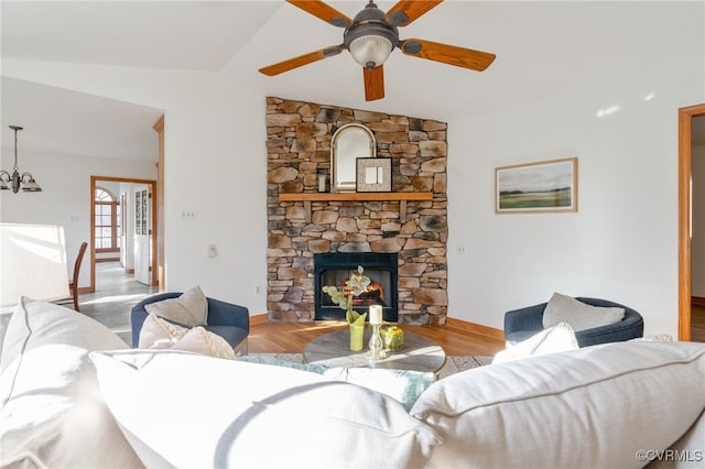 living room featuring a fireplace, light wood-type flooring, vaulted ceiling, and ceiling fan