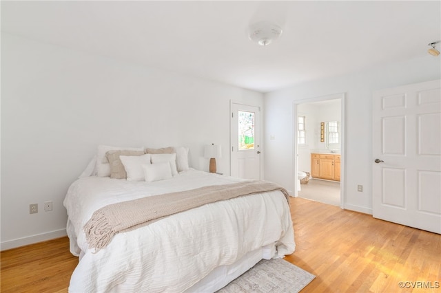 bedroom with ensuite bathroom and light hardwood / wood-style flooring