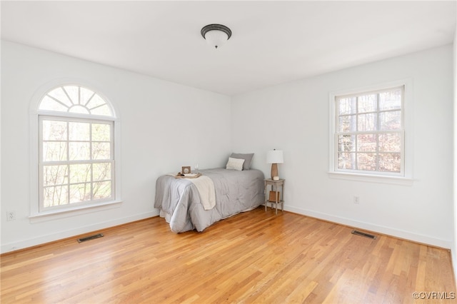 bedroom with light wood-type flooring and multiple windows