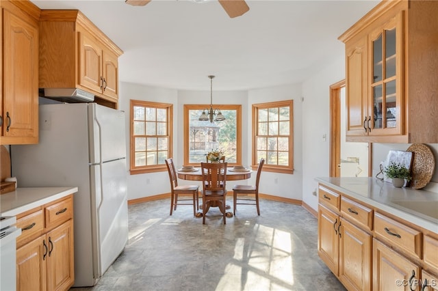 kitchen featuring light brown cabinetry, exhaust hood, decorative light fixtures, a chandelier, and white fridge