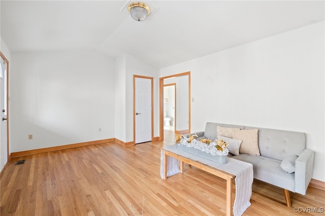 living room with light hardwood / wood-style floors and vaulted ceiling