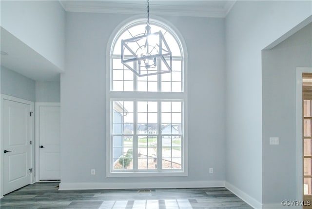 spare room featuring hardwood / wood-style floors, a notable chandelier, and crown molding