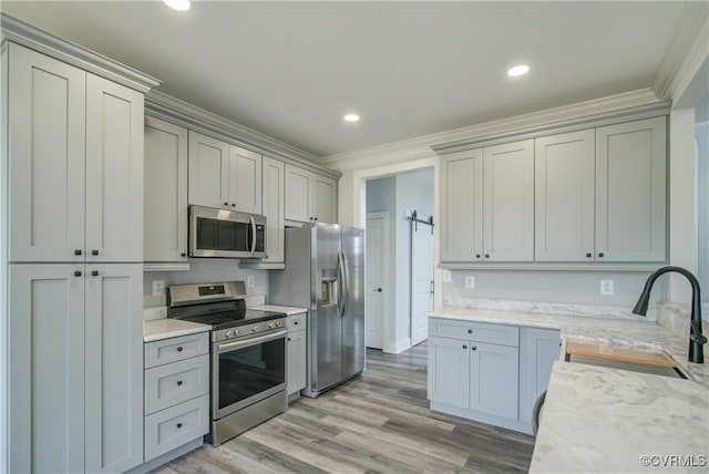 kitchen with light stone countertops, sink, light hardwood / wood-style flooring, crown molding, and appliances with stainless steel finishes