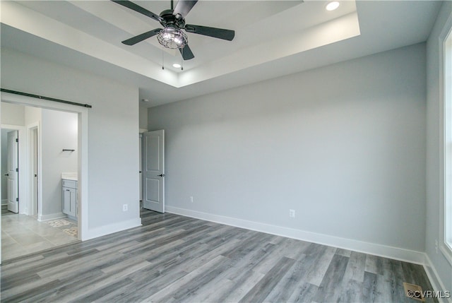 unfurnished bedroom with light wood-type flooring, ensuite bath, and ceiling fan