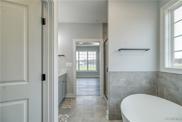 bathroom with tile patterned floors, plus walk in shower, plenty of natural light, and vanity