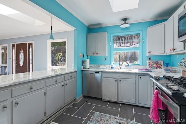 kitchen featuring a skylight, stainless steel appliances, sink, pendant lighting, and white cabinets