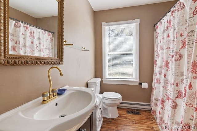 bathroom with plenty of natural light, hardwood / wood-style floors, a baseboard radiator, and toilet