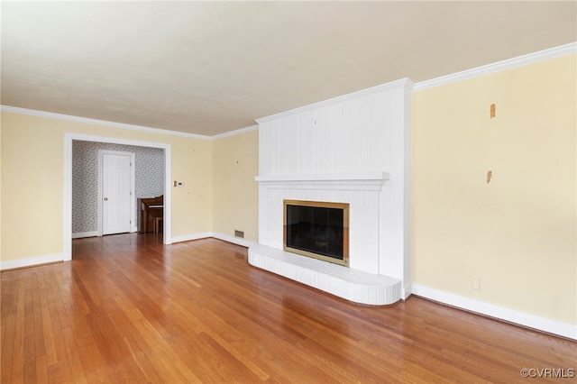 unfurnished living room featuring hardwood / wood-style flooring, ornamental molding, and a fireplace