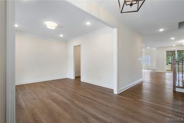 unfurnished room with an inviting chandelier, dark wood-type flooring, and ornamental molding