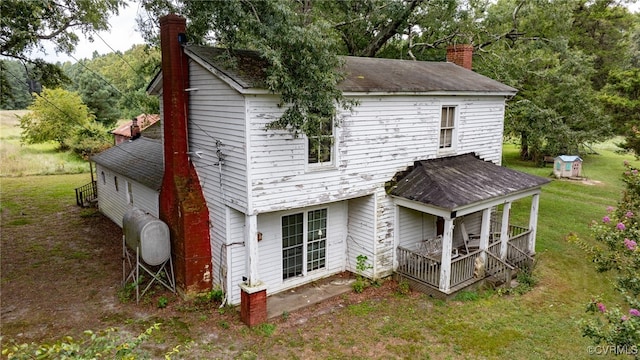 rear view of property with covered porch and a lawn