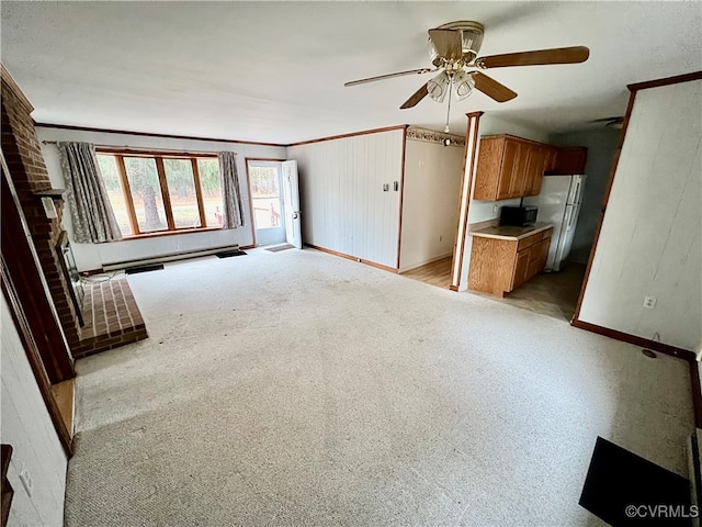 unfurnished living room featuring ceiling fan, light colored carpet, a fireplace, and crown molding