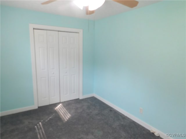 unfurnished bedroom with dark colored carpet, ceiling fan, and a closet