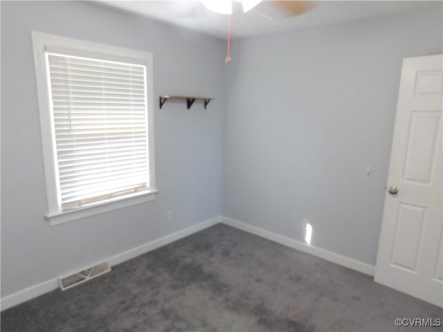 unfurnished room with dark colored carpet and ceiling fan