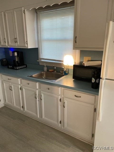 kitchen featuring light hardwood / wood-style floors, white refrigerator, white cabinetry, and sink